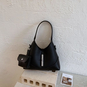 Detail of black lychee grain leather bag with silver piston buckle and small pouch