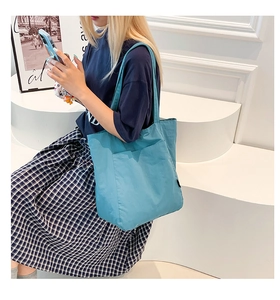 Detail of blue canvas tote bag with large front pocket and wide strap for daily use