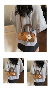 Detail view of a vintage brown leather cylinder bag with a cute plush bear charm accessory
