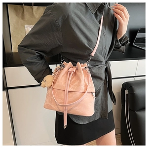Pink drawstring bucket bag with glossy crinkle texture and cute bear charm pendant