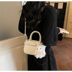 Detail view of cream white PU leather crossbody bag with cute plush rabbit charm