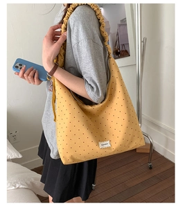 Close-up of a yellow polka dot tote bag featuring ruffled straps and Bonjour Merci label