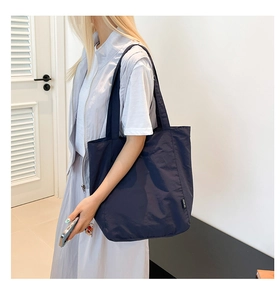 Close-up of deep blue tote bag side detail featuring minimalist black decorative tag