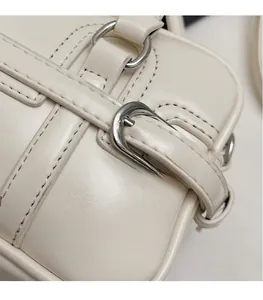 Close-up of cream leather shoulder bag showing silver hardware and fine stitching detail
