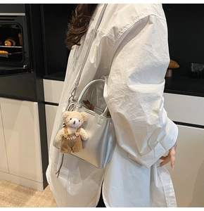 Silver metallic bucket bag shown with a cute teddy bear charm on a crossbody strap