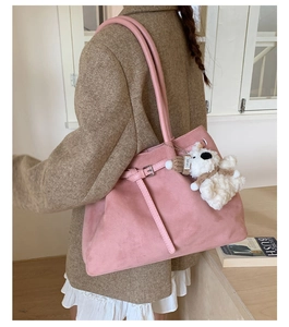 Detail view of the large pink suede tote bag worn by a model in a bright interior setting