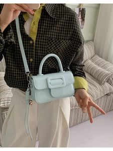 Detail shot of light blue mini square handbag with chunky buckle shown on model