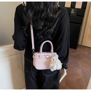 Detail of pink leather handbag with decorative buckle and cute plush bunny charm accessory