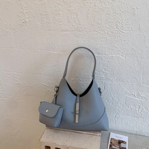 Detail view of dusty blue bucket bag featuring litchi texture and matching mini pouch