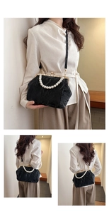 Detail view of black pleated shell bag with elegant pearl handle and vintage metal clasp
