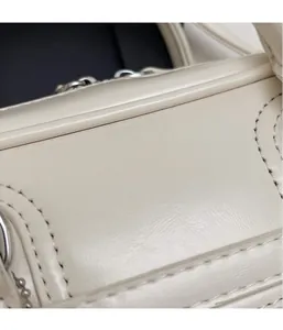 Detailed macro view of cream leather texture and stitching on the small crossbody bag