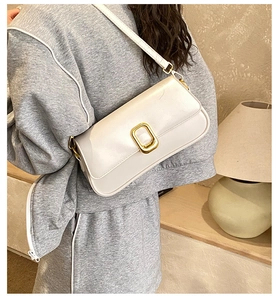 Close-up of a white leather square bag featuring a distinctive gold metal buckle and strap
