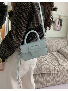 Detail of light blue leather handbag with square buckle and decorative side tassels