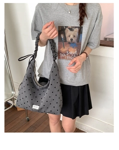 Close-up of gray polka dot canvas tote bag featuring ruffled strap and butterfly embroidery