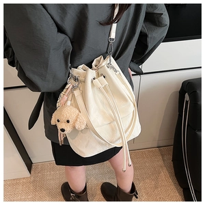 White bucket bag with drawstring closure and cute plush toy poodle charm accessory