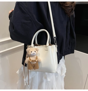White bucket bag with teddy bear pendant worn on model for stylish look and feel