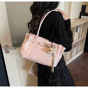 Pink glossy tote bag close-up with cute plush bear charm on a slim shoulder strap