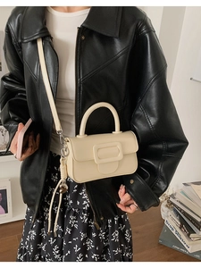 Close-up of cream leather square handbag with top handle and adjustable strap worn by model