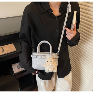 Detail of light grey crossbody bag with belt buckle decor and plush sheep keychain