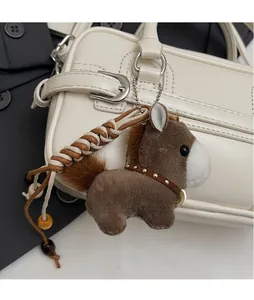 Detailed close-up of a cute brown and white plush pony charm on a white handbag