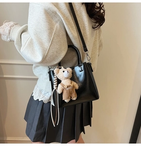 Detail view of black faux leather bucket bag with a cute bear charm on a model