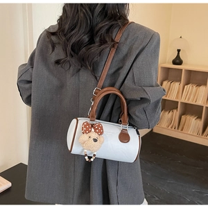 Detailed side view of the white pillow bag with brown straps and cute bear charm