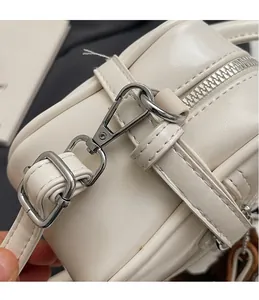 Close-up of durable silver metal hook and premium leather texture on white crossbody bag