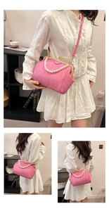 Detail of pink shell-shaped evening bag with pearl handle and pleated fabric texture