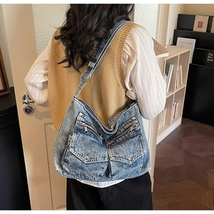Detail view of retro blue denim crossbody bag with two front pockets and metal buckles