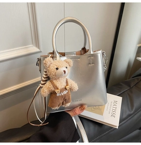 Detail showing metallic silver leather tote bag with a cute plush bear charm accessory