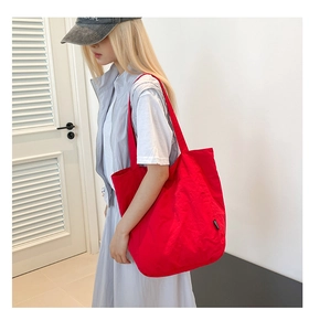Close-up of red high-capacity canvas tote bag featuring stylish side brand label details