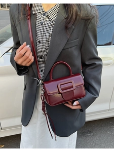 Outdoor lifestyle view of a burgundy leather crossbody bag with decorative square buckle