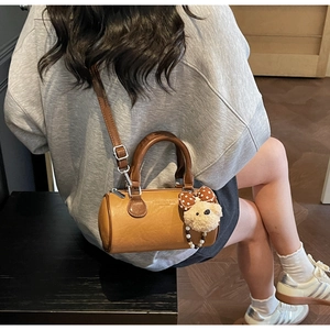 Detail of vintage caramel Boston bag with plush bear charm and wooden handles