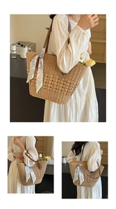 Detail of large woven straw tote bag with elegant floral scarf handle for beach vacation