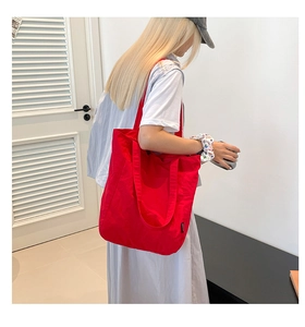 Detail of red large-capacity canvas tote bag showing the side seam and wide shoulder strap