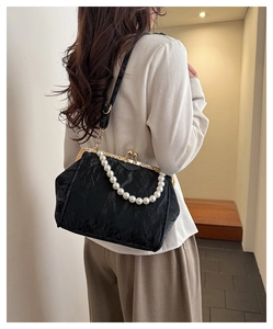 Detail of black pleated shell bag with vintage gold clasp and pearl handle chain