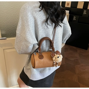 Detail view of vintage caramel Boston bag with plush bear charm and elegant leather texture