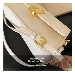 Detail view of the adjustable shoulder strap with gold buckle on a beige leather crossbody bag