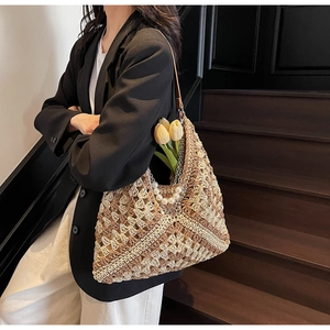 Detail of woven straw tote bag with crochet floral patterns and pearl handle accents
