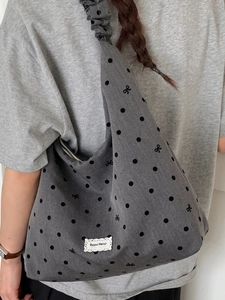 Grey canvas tote bag with black polka dots, bow patterns, and ruffled strap design