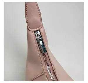 Close-up of a pink leather handbag featuring a shiny silver metal zipper and hardware