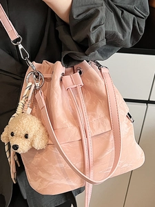 Pink textured bucket bag with drawstring closure and cute plush puppy charm pendant