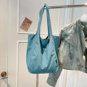 Detail of Morandi blue nylon tote bag showing side woven label and wide shoulder straps