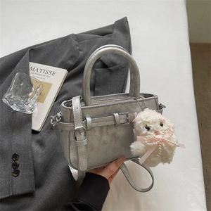 Detail of silver metallic handbag with rabbit charm and decorative buckle accent