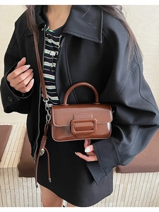 Detailed macro view of the brown glossy PU leather texture and decorative buckle of the bag