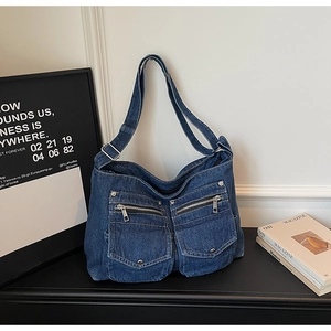 Detail of blue denim hobo bag featuring cargo utility pockets and metallic zippers