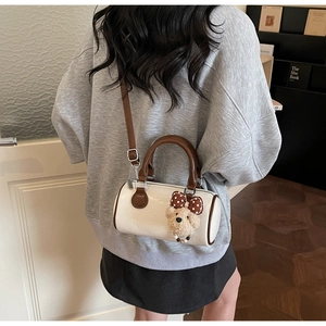 Detail of white vintage boston bag with brown handles and cute plush bear charm