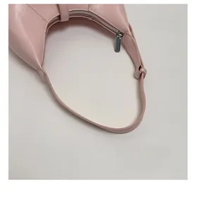 Detail view of smooth light pink crescent bag with silver zipper and textured handle strap