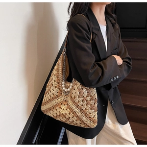 Detail of woven straw tote bag with elegant white pearl and silver chain shoulder strap