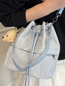 Chic light blue drawstring bucket bag with a plush bear charm for a casual spring look